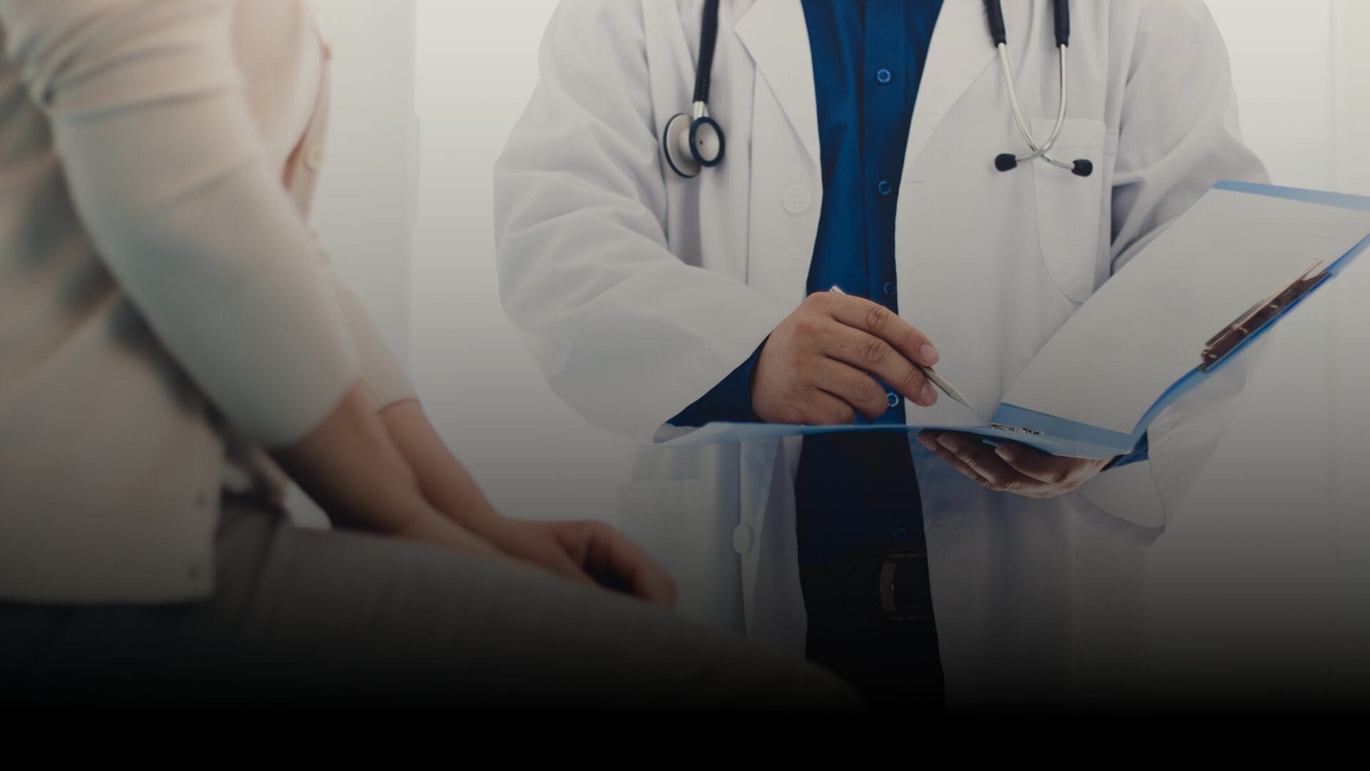 A patient speaks with a medical professional in an exam room setting.