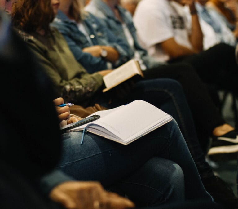 Students in an audience taking notes during a lecture