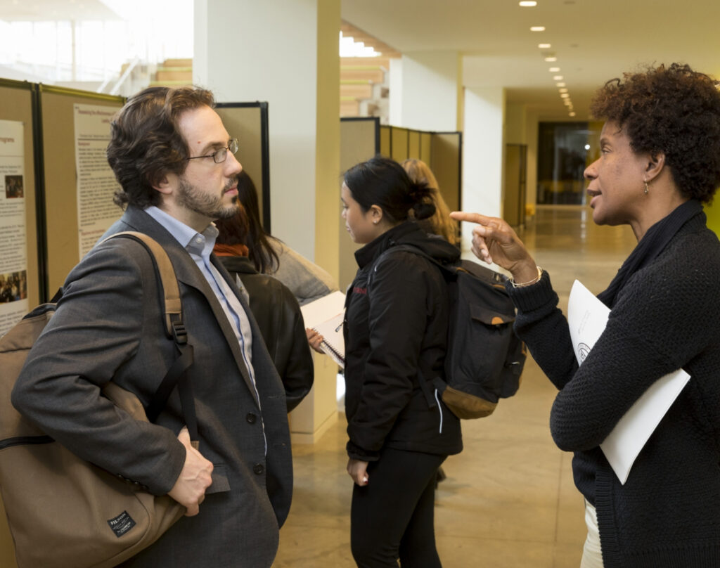 Two researchers attending a CCHEq event engage in discussion.