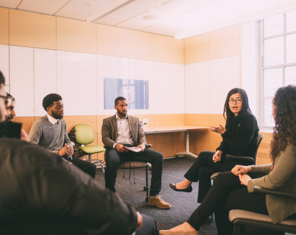 A group of students and researchers engage in discussion in a university classroom.