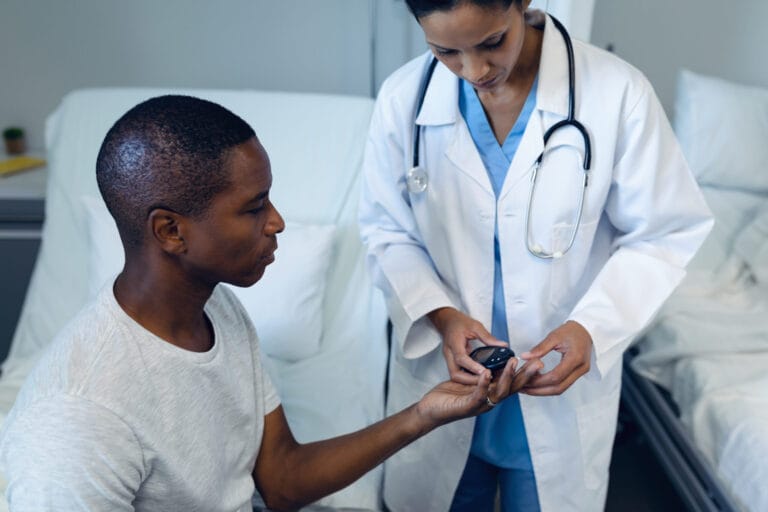 A female doctor takes a blood sample from a young black male pateint using a lancet pen.